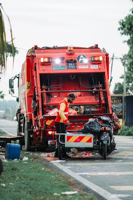 The image depicts a section of a white commercial van parked on a street, with its rear door partially visible. Near the back of the van, there are three large blue rubbish bags made of plastic, fille
